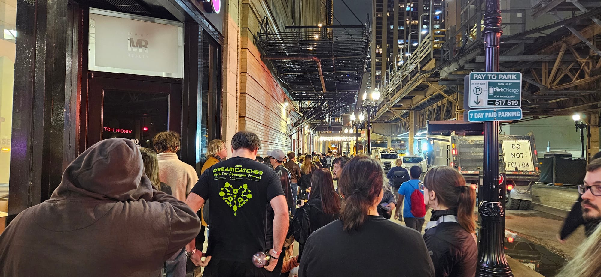 Line of Dreamcatcher fans down a sidewalk at night before doors opening.