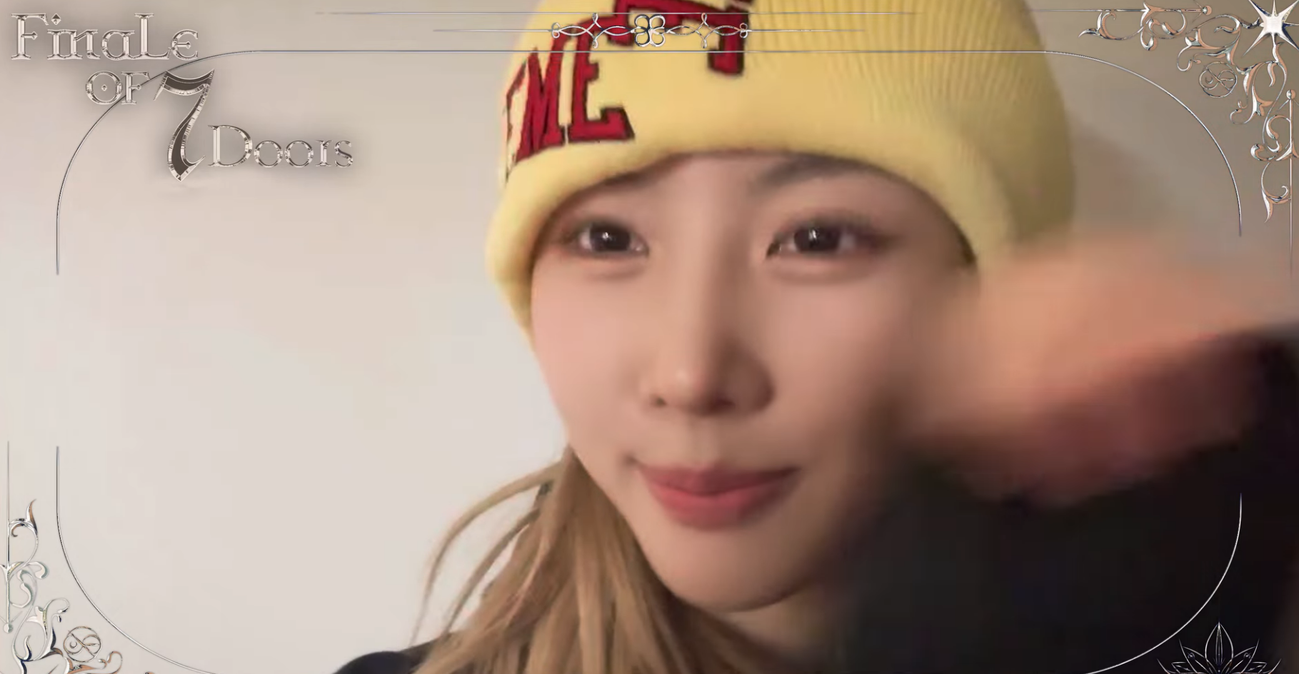 Yoohyeon waving and smiling in a yellow hat for the camera while reminding fans about their concert.