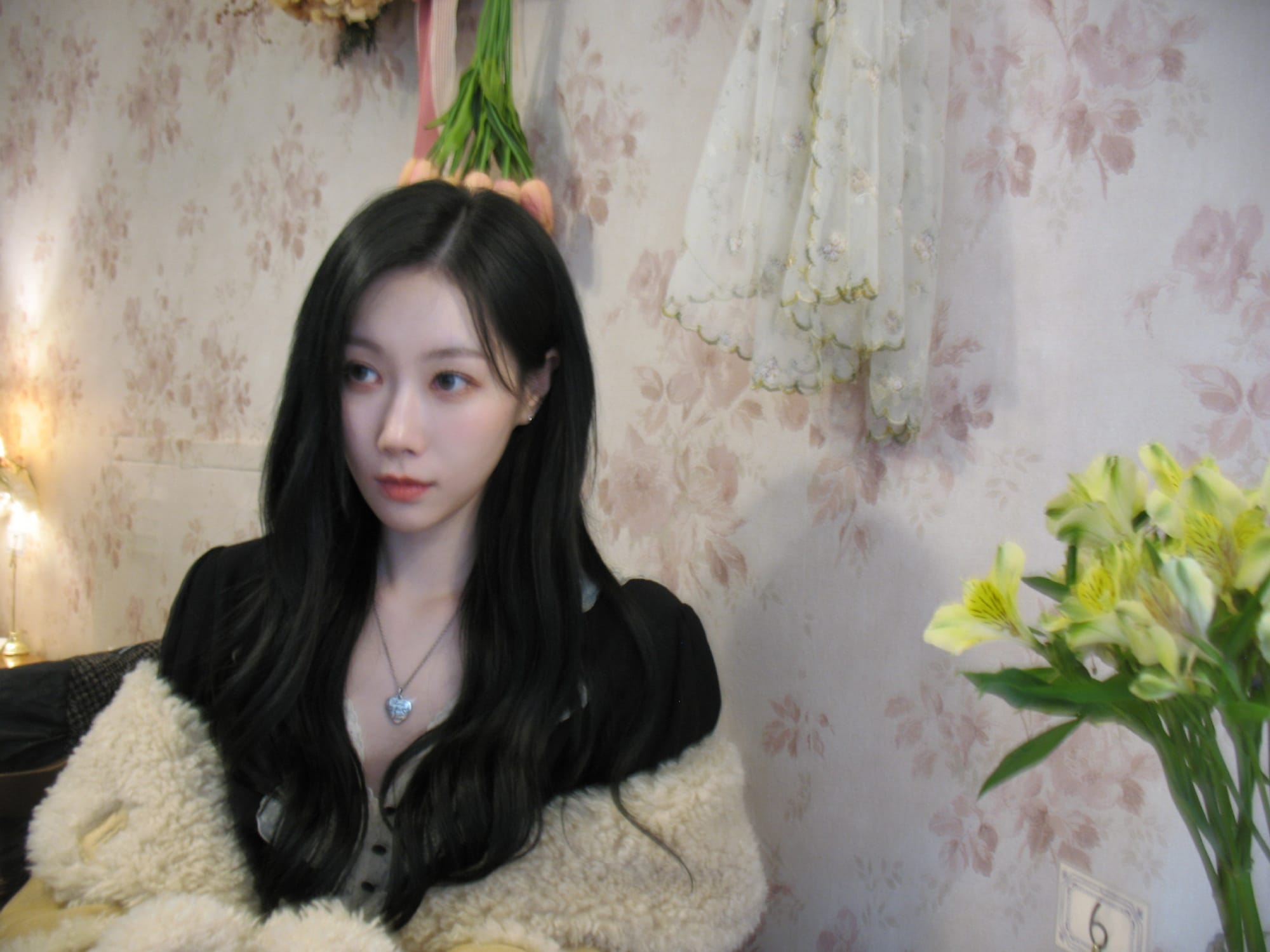 Handong in a black blouse and tan fur-lined coat posing for the camera.