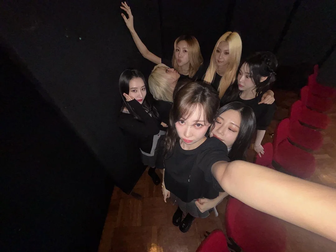 Dreamcatcher members taking a selfie dressed in black at a concert venue.