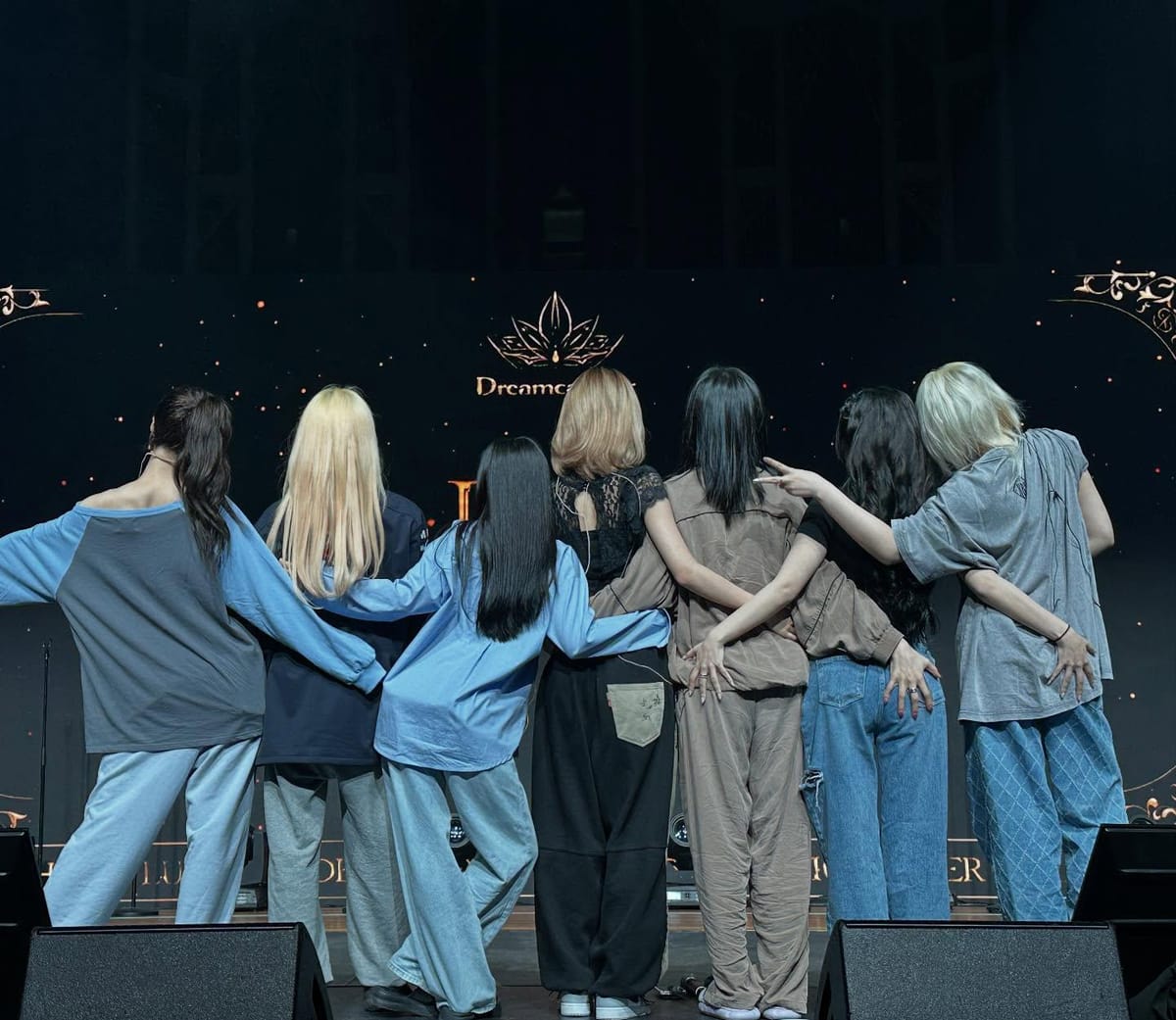 Dreamcatcher with their backs to the camera looking at their stage logo LED.