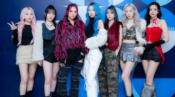 Blue background for Inkigayo music show with Dreamcatcher members dressed fashionably.