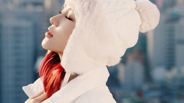 Dreamcatcher's Siyeon, with red hair and dressed in white winter clothes, singing.