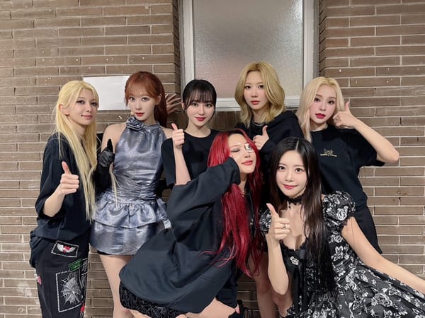 Dreamcatcher group picture against a brick background, dressed in stage outfits.