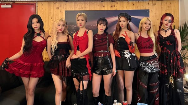 Dreamcatcher dressed in red and black in their dressing room, posing for the camera.