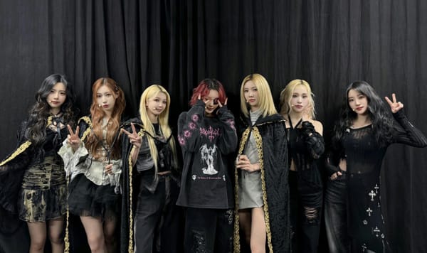 Dreamcatcher's members in the official Dreamcatcher Robes, pose in front of a black curtain.