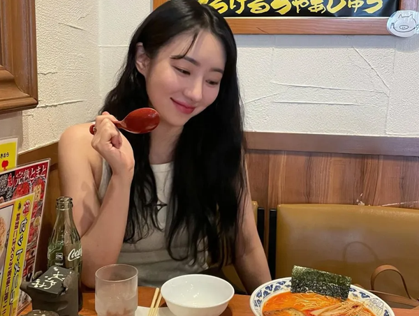 SuA smiling in anticipation of her ramen meal in a restaurant in Osaka, Japan