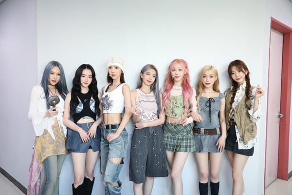 Dreamcatcher, dressed in casual clothes, smiling and posing against a white backdrop for a music show.
