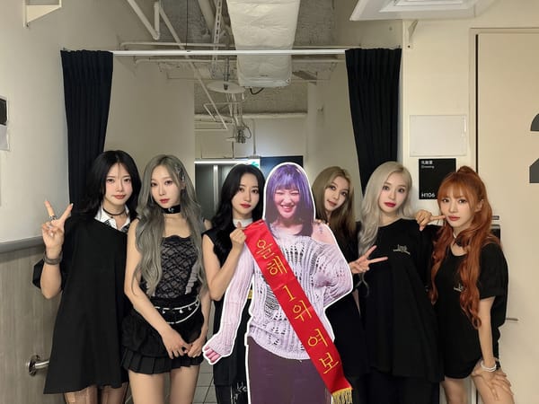 Dreamcatcher dressed in black, with a life-sized Siyeon cut-out for a group conert photo.