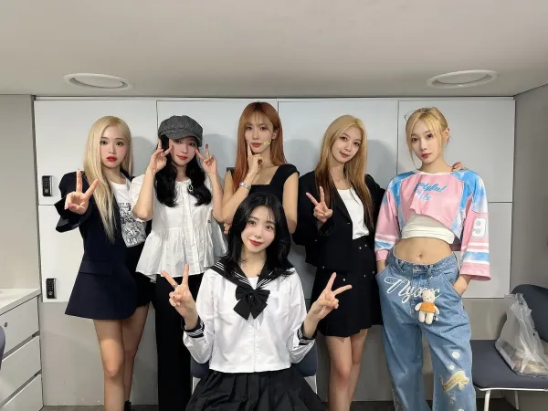 Dreamcatcher smiling with "V" poses for the camera in a small room.