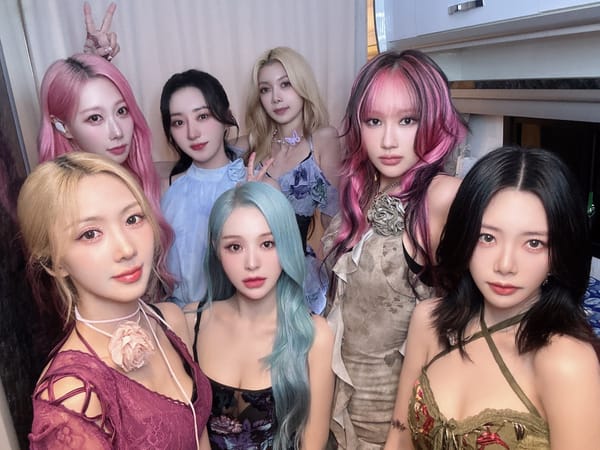 Dreamcatcher, dressed in summer dresses, takes a group photo as they smile for the camera.