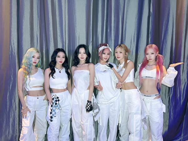 Dreamcatcher, dressed in white against a silver curtain, poses for the camera after Mexico CIty performance.