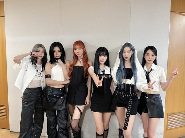 Dreamcatcher smiling and posing with victory signs dressed in black and white.