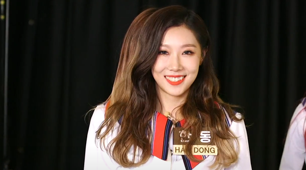 Handong with brown hair and white and red outfit smiling for the camera.